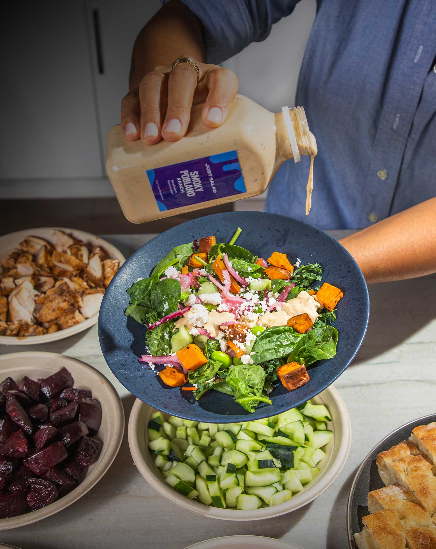 person drizzling salad with dressing
