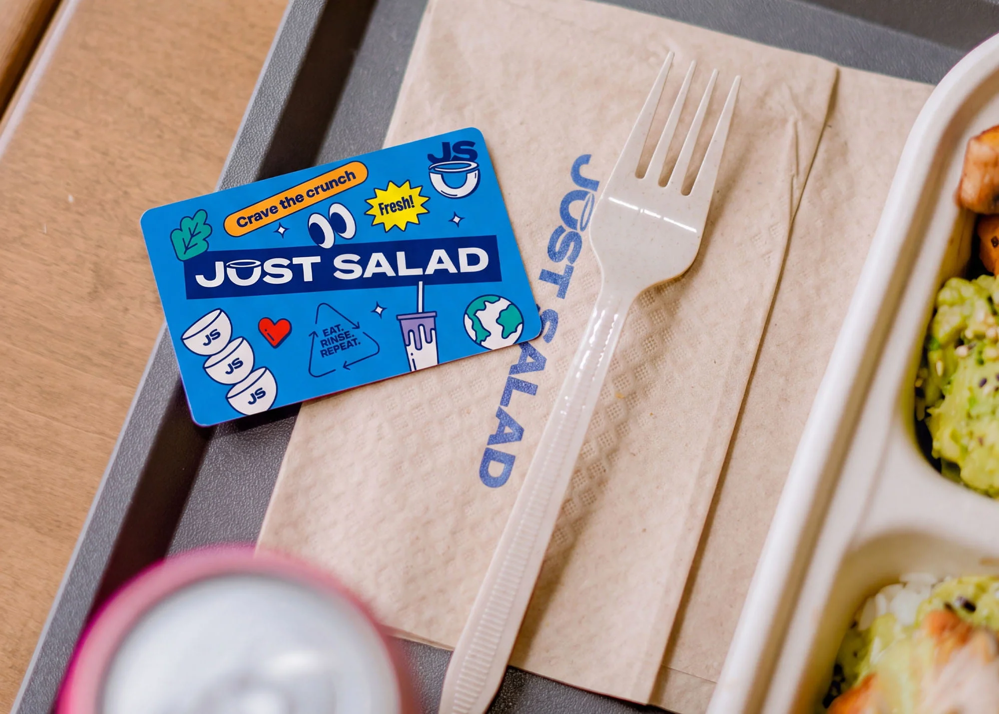 A blue Just Salad gift card on a tray beside a meal