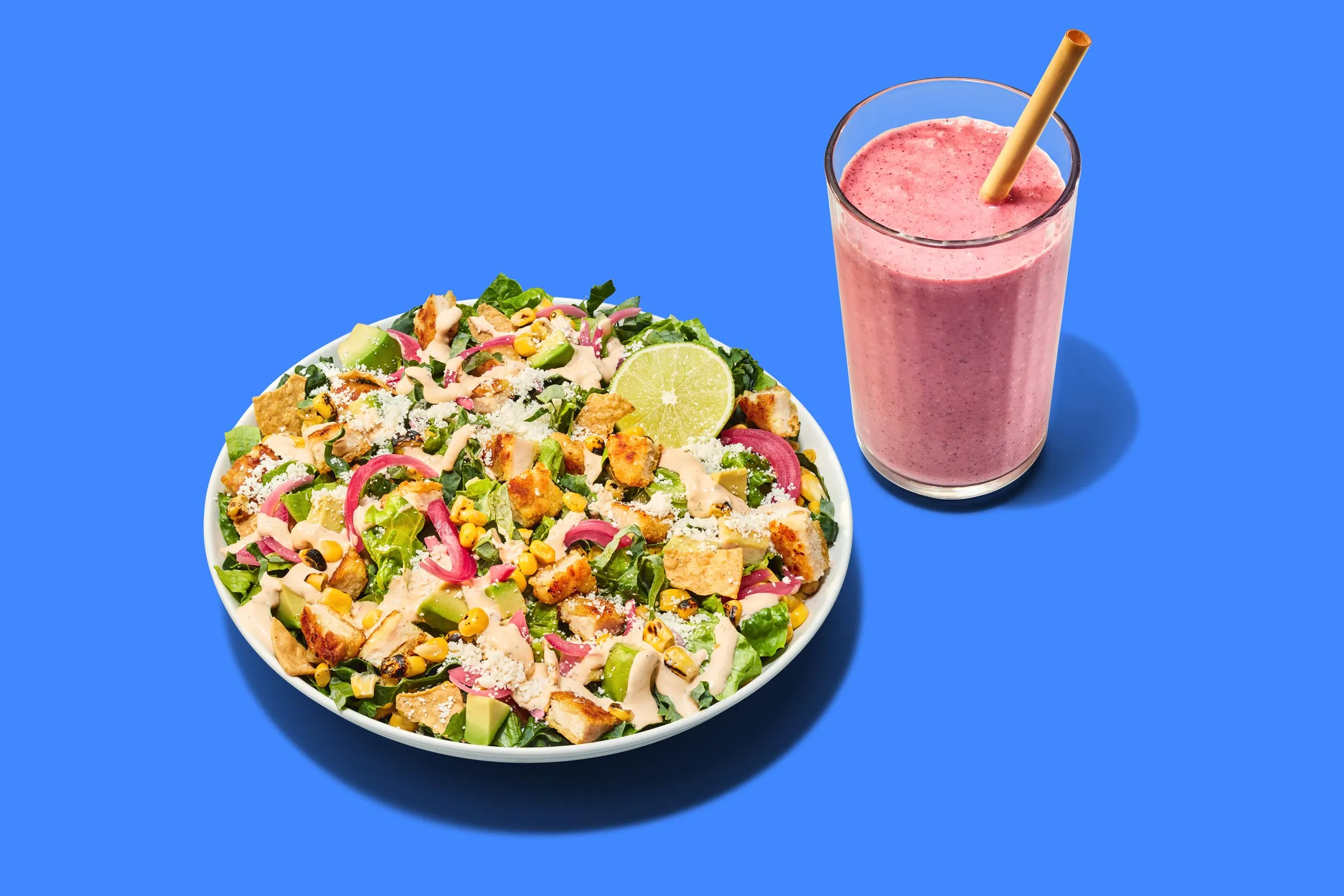 A salad and smoothie on a solid background