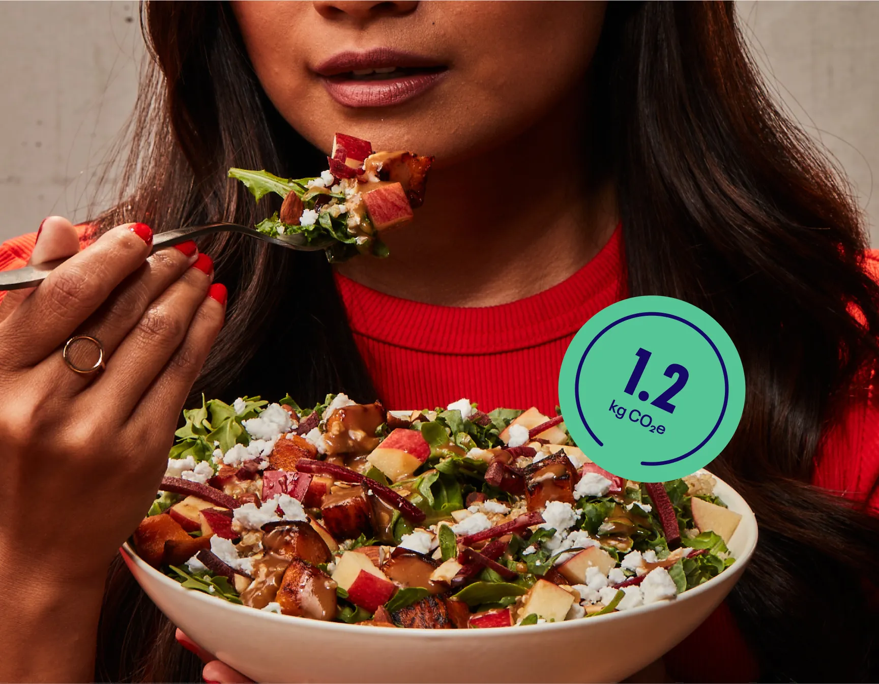 Person eating a salad with a carbon emissions stat badge