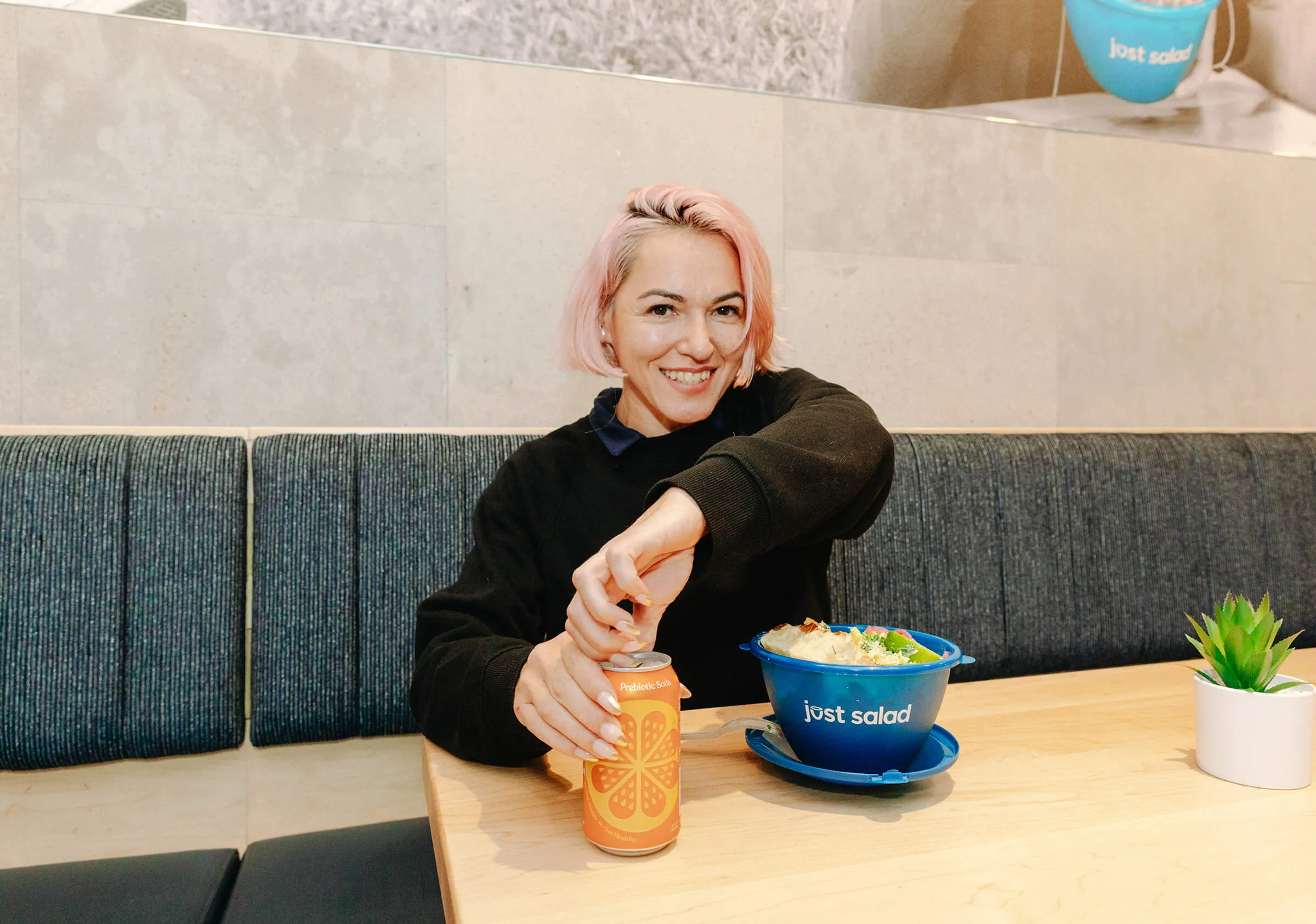 A person opening a prebiotic soda with a salad